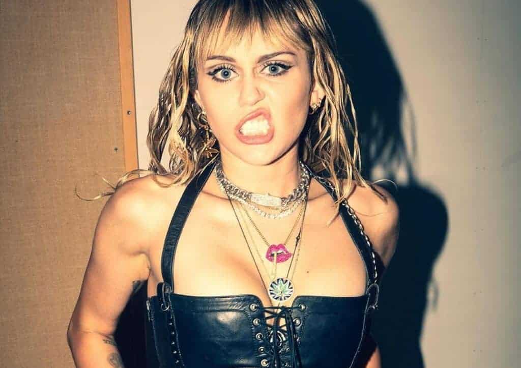 Miley Cyrus z wyrazistym wyrazem twarzy i modnym strojem.