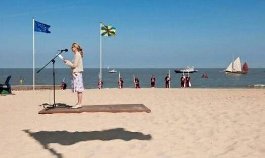 Kobieta czytająca książkę na plaży z widokiem na morze.