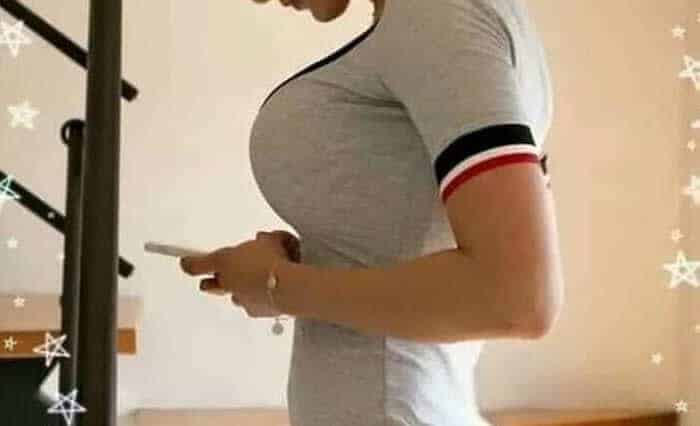 Kobieta w sportowym stroju korzysta z telefonu w domu.