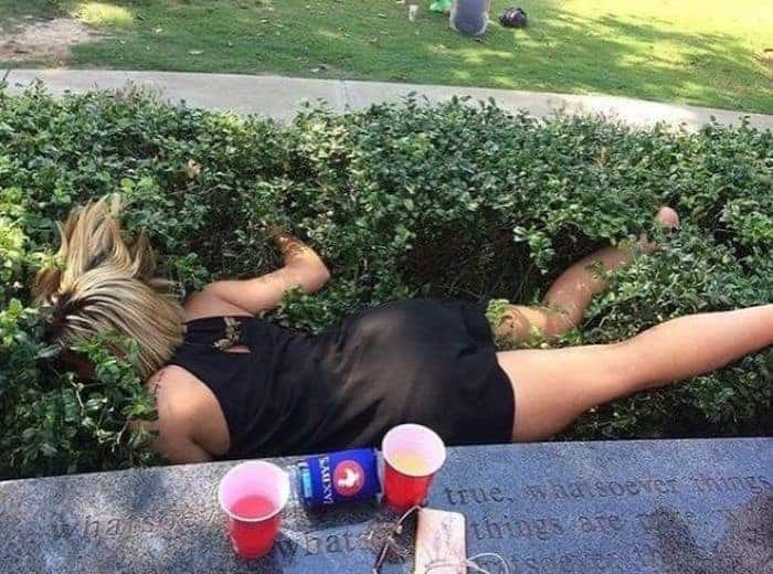 Osoba leżąca na trawniku po spożyciu alkoholu.