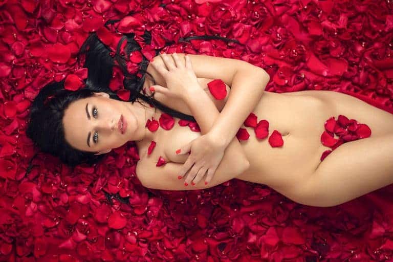Kobieta na różowych płatkach, artystyczna fotografia sensualna.