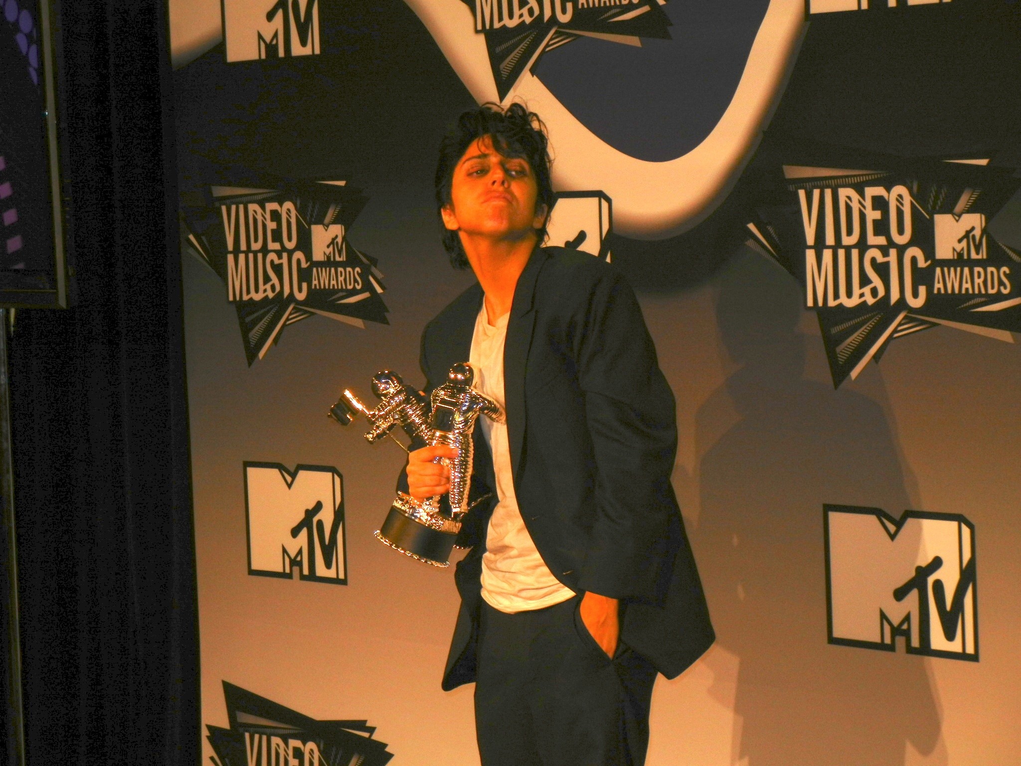 Lady Gaga w roli Jo Calderone trzyma dwie nagrody MTV VMA 2011, ubrana w czarny garnitur i białą koszulkę