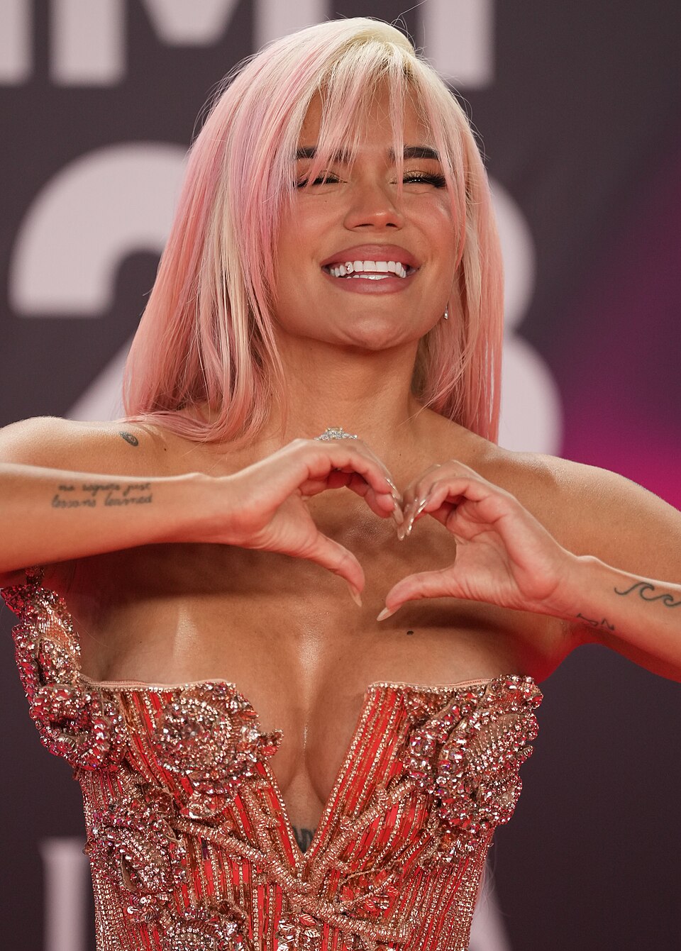 Karol G na Latin Grammy 2023 w Sewilli Karol G z różowymi włosami i w błyszczącej sukni układa dłonie w serce podczas Latin Grammy 2023