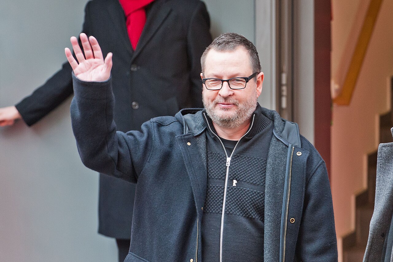 Lars von Trier podczas Berlinale 2014 Reżyser Lars von Trier w ciemnej kurtce i okularach pozdrawia fotoreporterów po konferencji filmu Nimfomanka na Berlinale 2014