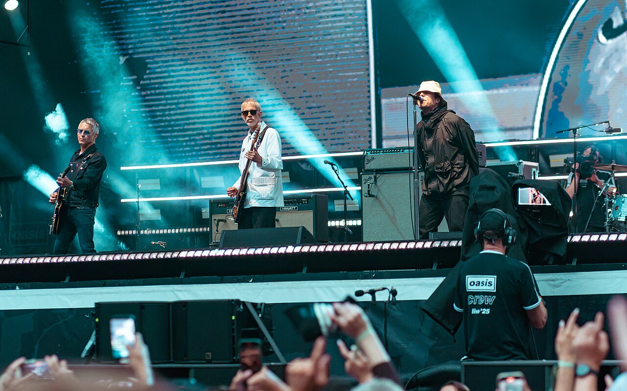 Oasis na Wembley 2025 - Liam i Noel z zespołem Noel Gallagher z gitarą po lewej i Liam Gallagher w jasnym kapeluszu po prawej występują z Oasis na Wembley 3 sierpnia 2025 roku