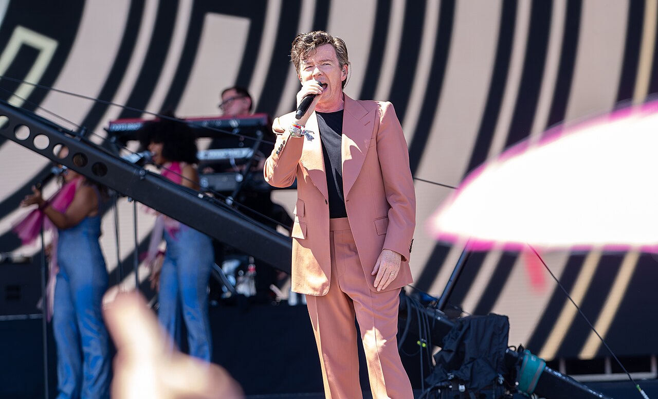 Rick Astley na scenie Glastonbury 2023 - drugie ujęcie Rick Astley podczas koncertu w czerwcu 2023 roku, śpiewa do mikrofonu na scenie Glastonbury