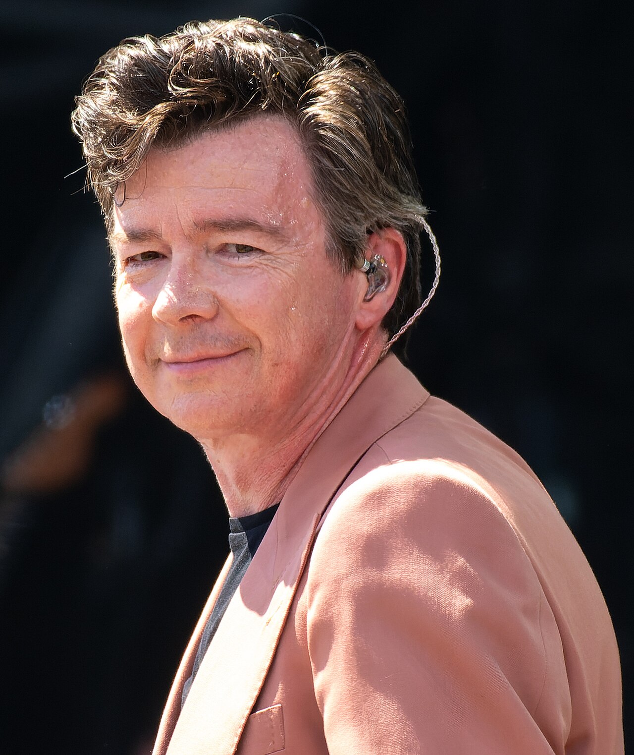 Rick Astley śpiewa w różowym garniturze na Pyramid Stage festiwalu Glastonbury 24 czerwca 2023 roku